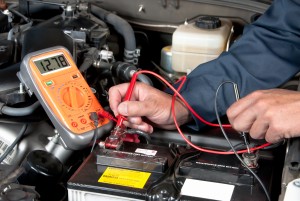 技工用万用表检查汽车电池电压的图像。