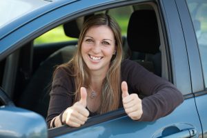 快乐的女司机探出车窗，竖起大拇指。